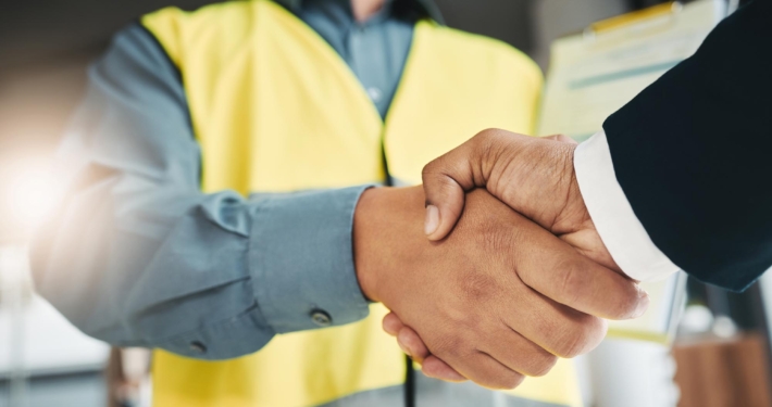 Side view of construction worker and man in suit shaking hands Side view of construction worker and man in suit shaking hands