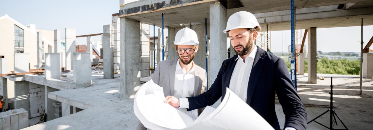Side view of two men in suits looking at blueprints