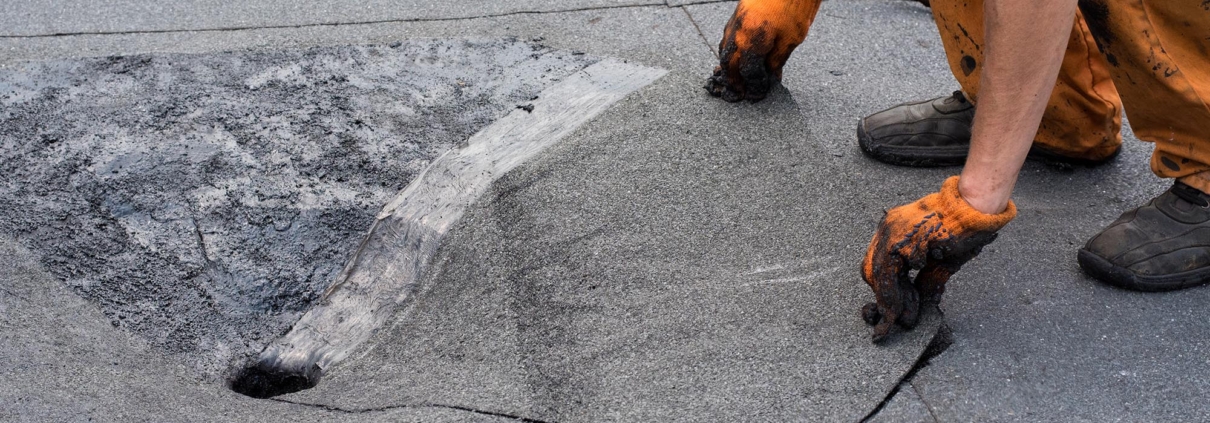 Worker installing material around flat roof drain