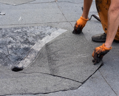 Worker installing material around flat roof drain