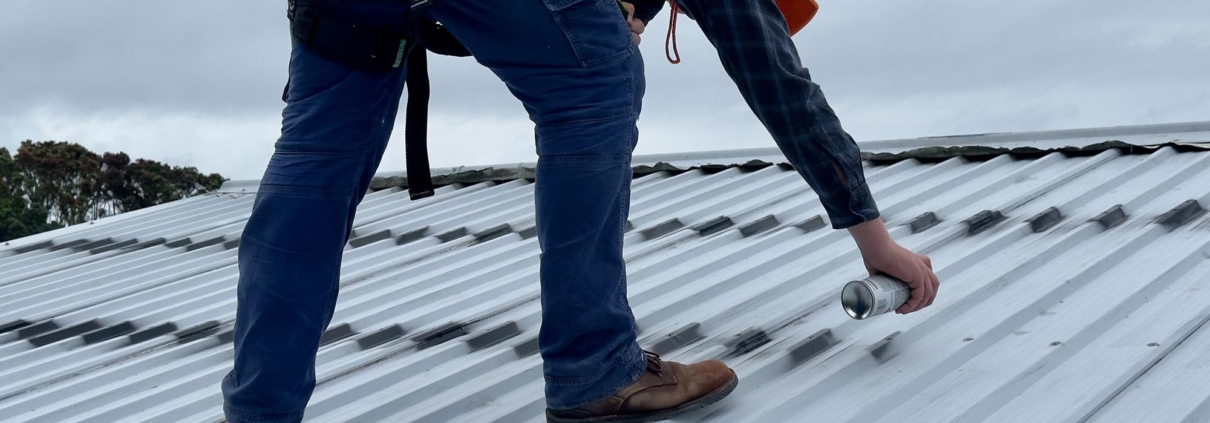 Worker patching commercial metal roof