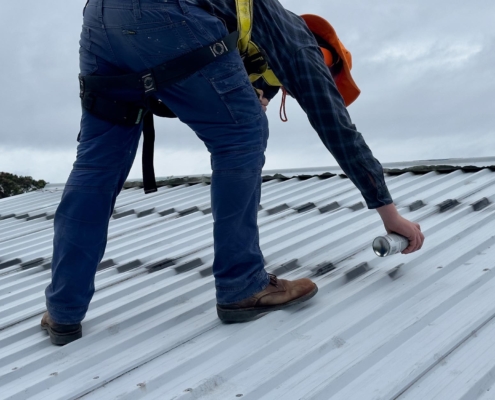 Worker patching commercial metal roof