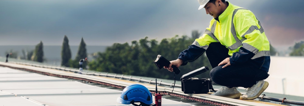 Worker using infrared camera to find leaks on roof
