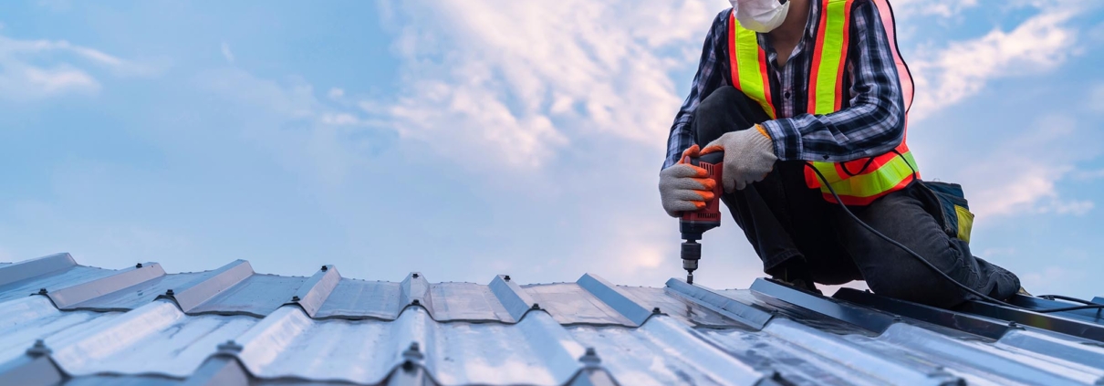 Worker drilling into metal roof