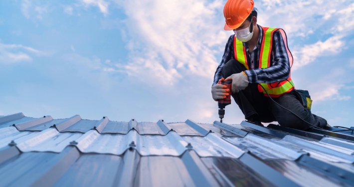 Worker drilling into metal roof Worker drilling into metal roof